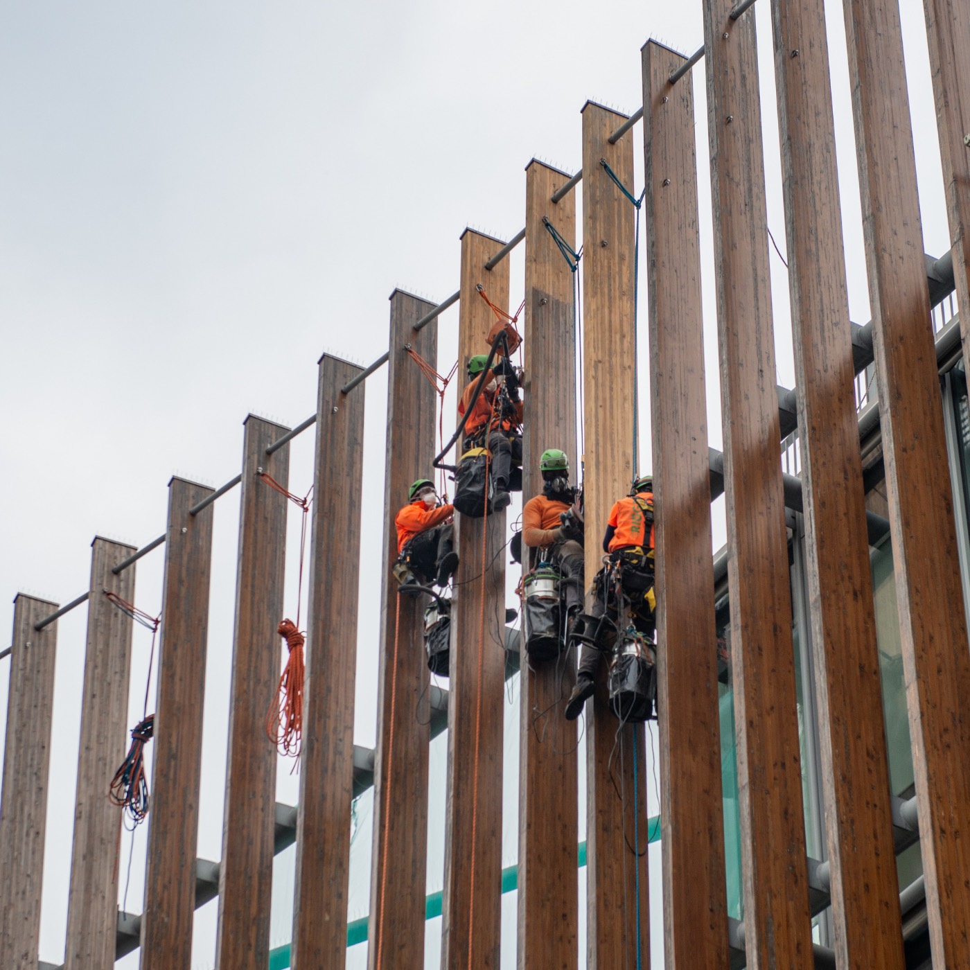 Rope access technicians working on a tall industrial building facade
