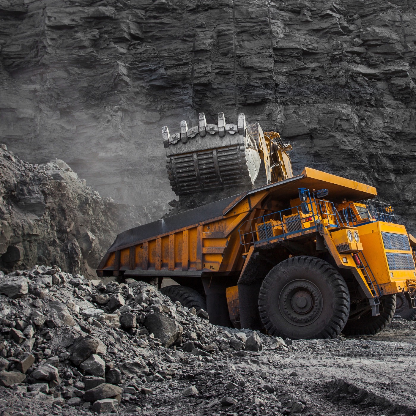 Large yellow mining truck beside a rocky wall