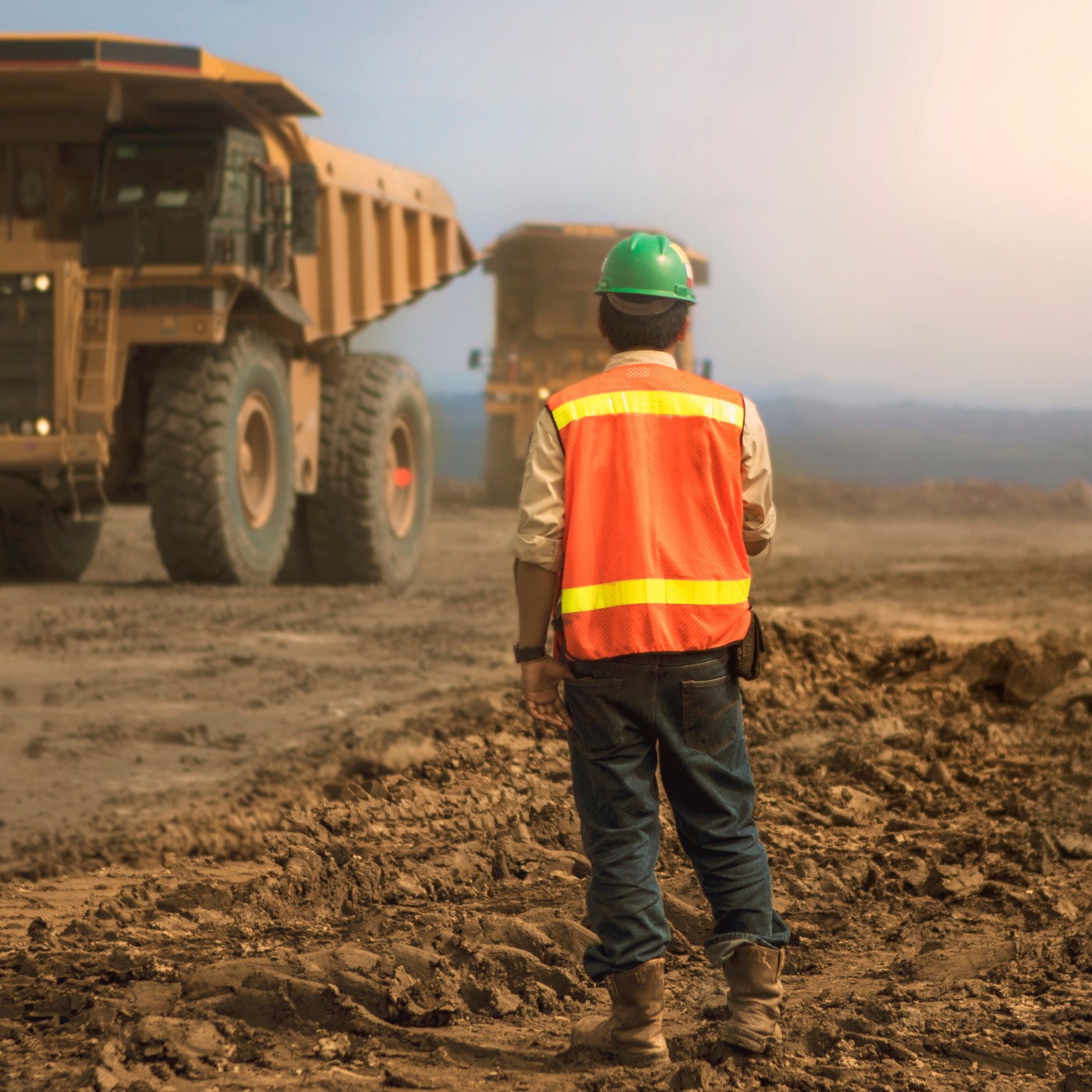 Site supervisor in high visibility PPE coordinating large mining vehicles